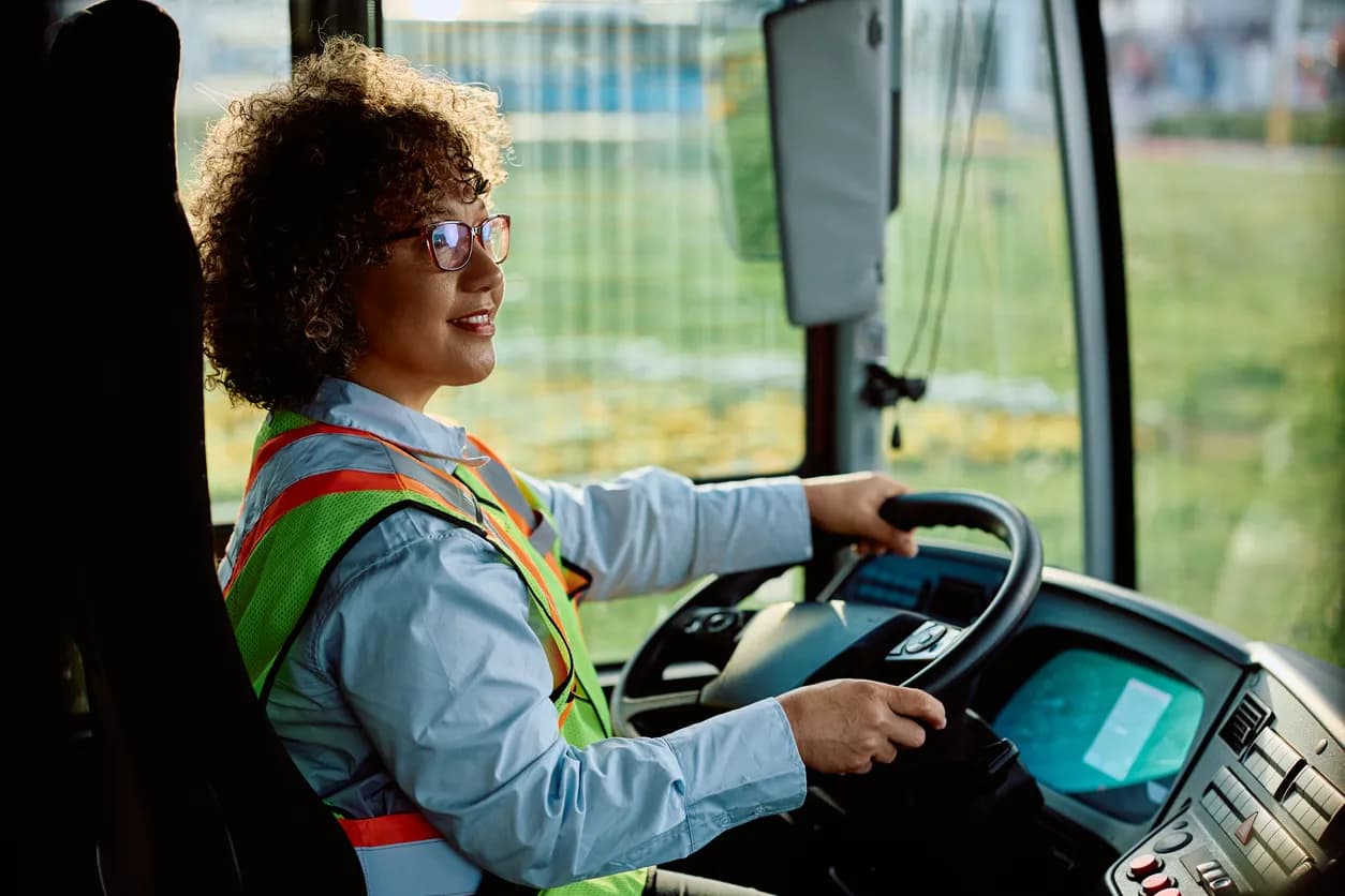 Busschaufför i reflexväst bakom ratten i bussen
